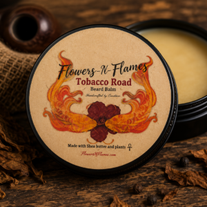 Flowers N Flames Tobacco Road Beard Balm in a black tin with a kraft label, handcrafted with botanical ingredients and a warm tobacco-inspired fragrance on a rustic wooden surface.