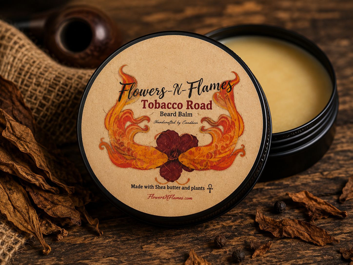 Flowers N Flames Tobacco Road Beard Balm in a black tin with a kraft label, handcrafted with botanical ingredients and a warm tobacco-inspired fragrance on a rustic wooden surface.