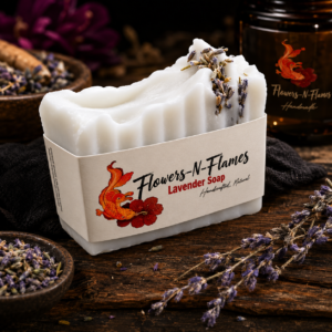 Handcrafted Flowers N Flames Lavender Soap displayed on a rustic wooden surface with dried lavender buds and fresh lavender sprigs, wrapped in the signature kraft paper cigar band featuring the Flowers N Flames koi fish and hibiscus logo.